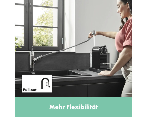 Küchenszene mit Spültischarmatur mit Ausziehfunktion und einer Frau, die eine Kaffeemaschine befüllt