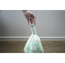 Une main tient un sac poubelle pour déchets organiques