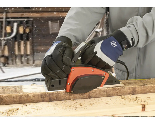 Une personne rabote une planche de bois avec un rabot électrique à l''extérieur.