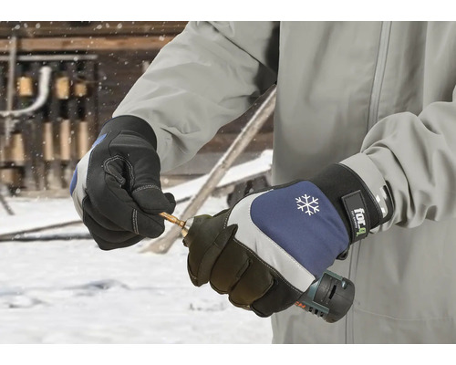 Une personne porte des gants de travail et tient une perceuse.