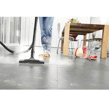 Dampfreiniger im Einsatz auf Fliesenboden in einem Wohnraum.