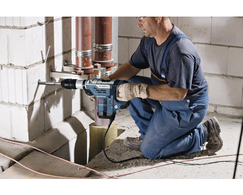 Ein Mann bohrt mit einem Bohrhammer ein Loch in eine Wand aus Porenbetonsteinen.