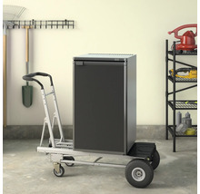 Réfrigérateur sur un chariot de transport dans un garage avec des outils de jardinage accrochés au mur