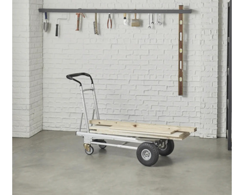 Diable avec chargement en bois devant un mur de briques avec suspension à outils