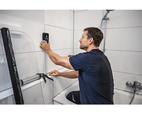 Mann benutzt Wandscanner im Badezimmer zur Badrenovierung.