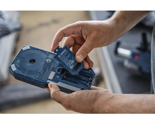 Mann setzt Batterie in Bosch Ortungsgerät ein