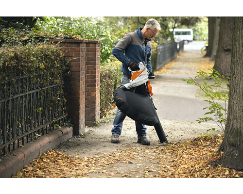 Un homme utilise un aspirateur de feuilles à batterie STIHL pour enlever les feuilles.