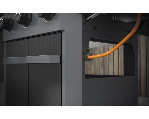 Vue détaillée d''un gril à gaz avec des éléments d''armoire et une conduite de gaz.