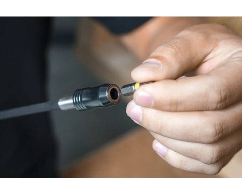 Une main insère un embout de vissage dans une rallonge de porte-embout.