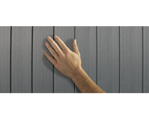 Main touchant un bardage de façade en plastique gris