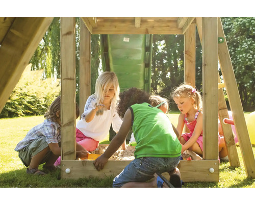 Kinder spielen in einem Sandkasten mit Spielturm im Garten.