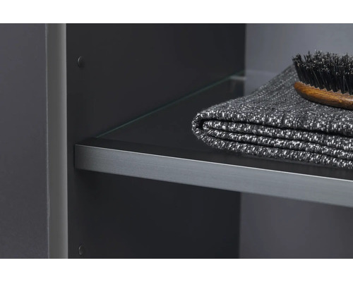 Detailaufnahme eines Badezimmerschranks mit Glasregal, Handtuch und Bürste