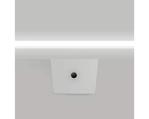 Un lavabo à poser blanc avec un bouchon de vidange rond et foncé.