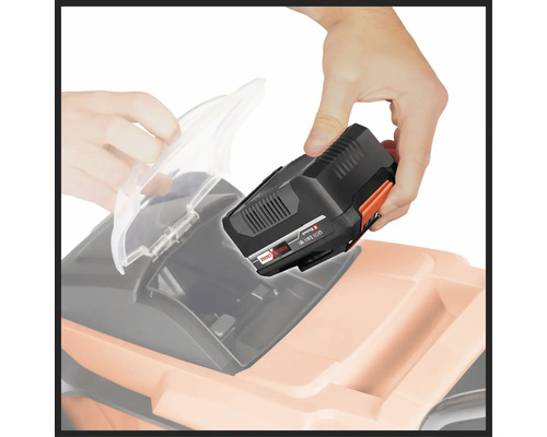 Un homme insère une batterie dans une tondeuse à gazon.