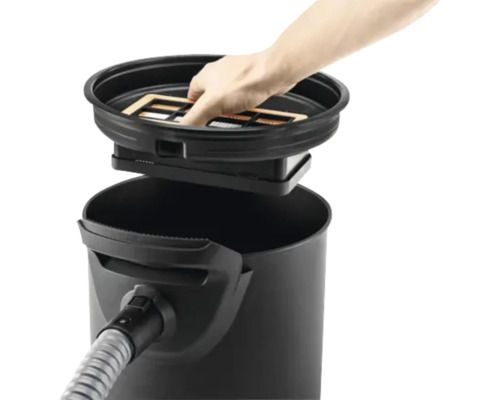 Une main place un filtre dans un aspirateur.