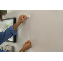 Femme fixant un rail pour tableaux au mur