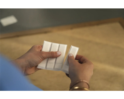 Une personne tient un paquet de bandes adhésives dans sa main.