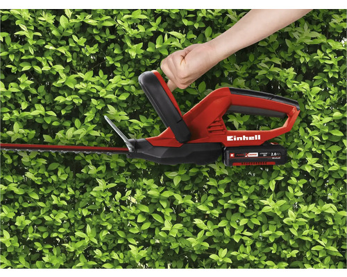 Utilisation d''un taille-haie sans fil Einhell devant une haie verte