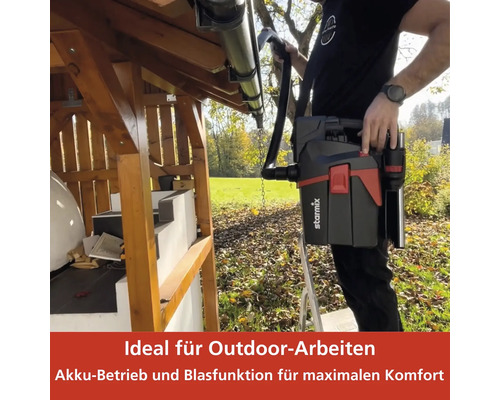 Eine Person reinigt mit einem tragbaren Staubsauger eine Dachrinne im Aussenbereich.