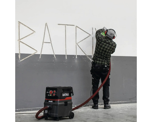 Handwerker arbeitet an einer Wand mit einem Industriesauger der Marke Starmix Batrix.