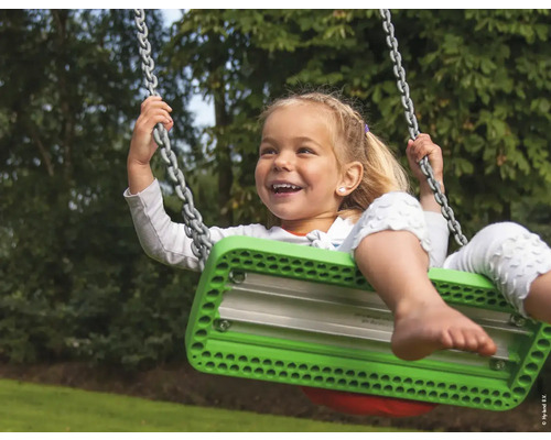 Un enfant se balance sur une balançoire avec suspension à chaîne dans le jardin.