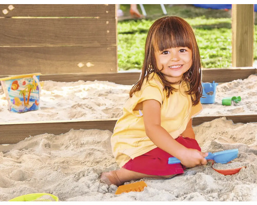 Enfant jouant dans un bac à sable avec des jouets de sable