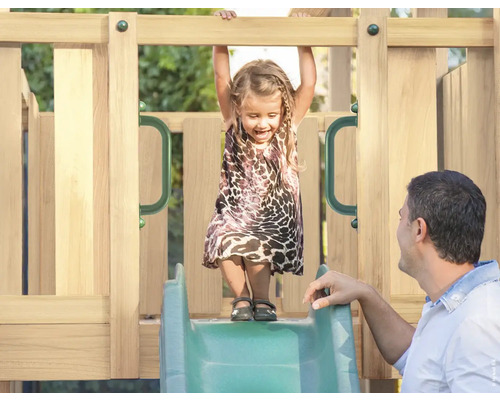 Fille sur un toboggan en bois avec son père dans le jardin.