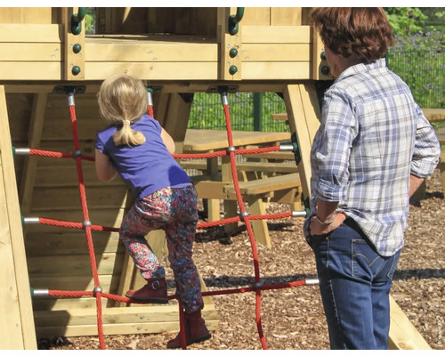 Une fille grimpe sur une aire de jeux avec une structure en filet pendant qu''une femme regarde.