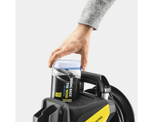 Une main place du shampoing auto Kärcher sur un nettoyeur haute pression