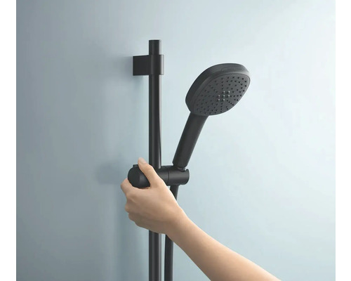 Main tenant une barre de douche noire et une douchette.