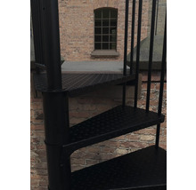 Detailansicht einer schwarzen Wendeltreppe aus Metall vor einer Backsteinmauer.