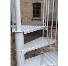 Detailaufnahme einer weissen Wendeltreppe vor einer Backsteinmauer.