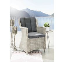 Geflochtener Sessel mit Armlehnen und grauen Kissen auf einer Terrasse mit Meerblick