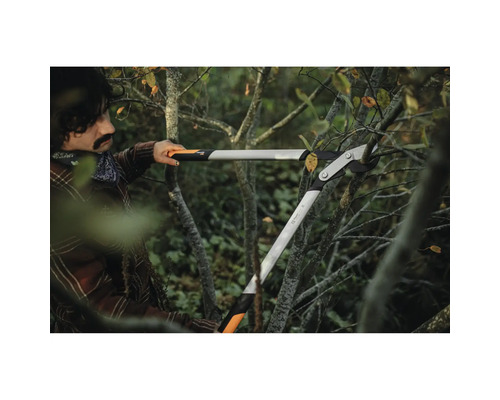 Une personne utilise un ébrancheur à crémaillère pour couper des branches.