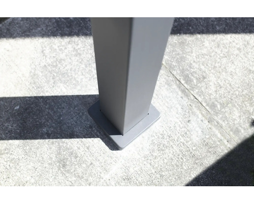 Vue détaillée d''une fixation de poteau d''abri de terrasse grise sur un sol en béton.