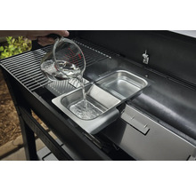Une personne verse de l''eau d''un verre doseur dans un récipient en acier inoxydable d''un barbecue.