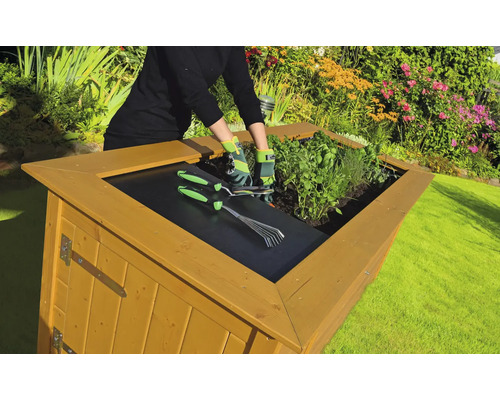 Jardinière surélevée avec des herbes aromatiques, des outils de jardinage et une personne dans un jardin