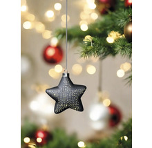 Sternförmiger Christbaumschmuck mit Lichtpunkten hängt an einem Weihnachtsbaum.