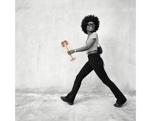 Frau geht mit einer Tischleuchte.