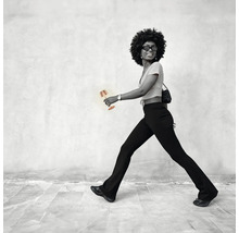 Frau mit Tischleuchte vor einer Wand gehend