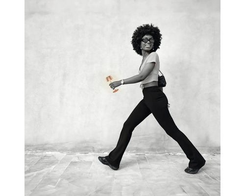 Frau mit Tischleuchte vor einer Wand gehend