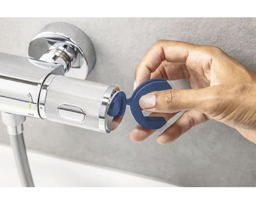 La main fixe un limiteur d''étranglement au mitigeur thermostatique