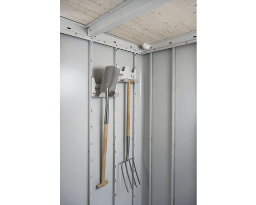 Vue intérieure d''un abri de jardin avec des outils de jardin tels qu''une bêche et une fourche à fumier sur un support