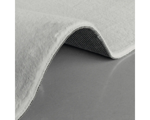 Detailansicht eines hellen Teppichs mit Flor und gewebter Rückseite