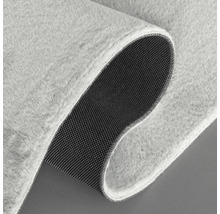 Detailansicht eines hellen Teppichs mit weicher Oberfläche und rutschfester Unterseite