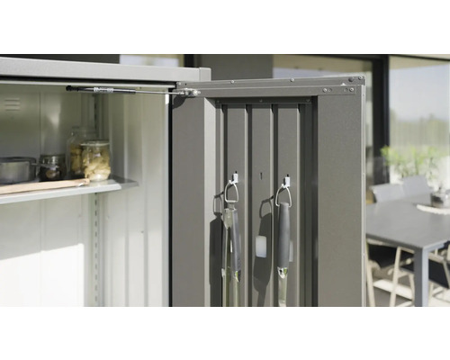 Geöffneter Geräteschrank mit Regalböden und Grillutensilien an der Tür