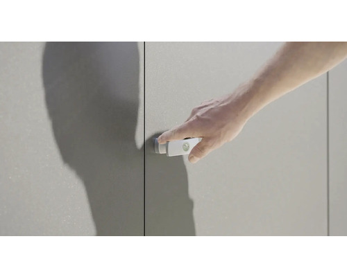 Un homme actionne un loquet de porte d''armoire sur une armoire grise.