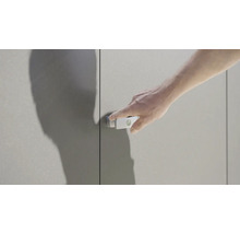 Une main actionne un loqueteau de placard sur une porte de placard.