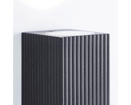 Lavabo foncé avec surface rainurée sur un mur blanc