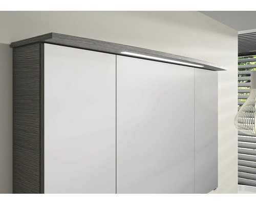 Kleiderschrank mit weissen Fronten, dunklem Korpus in Holzoptik und integrierter LED-Aufsatzleuchte am Kranz.